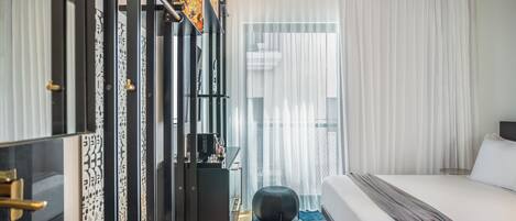 A modern hotel room with a large bed, a desk, and a wardrobe.