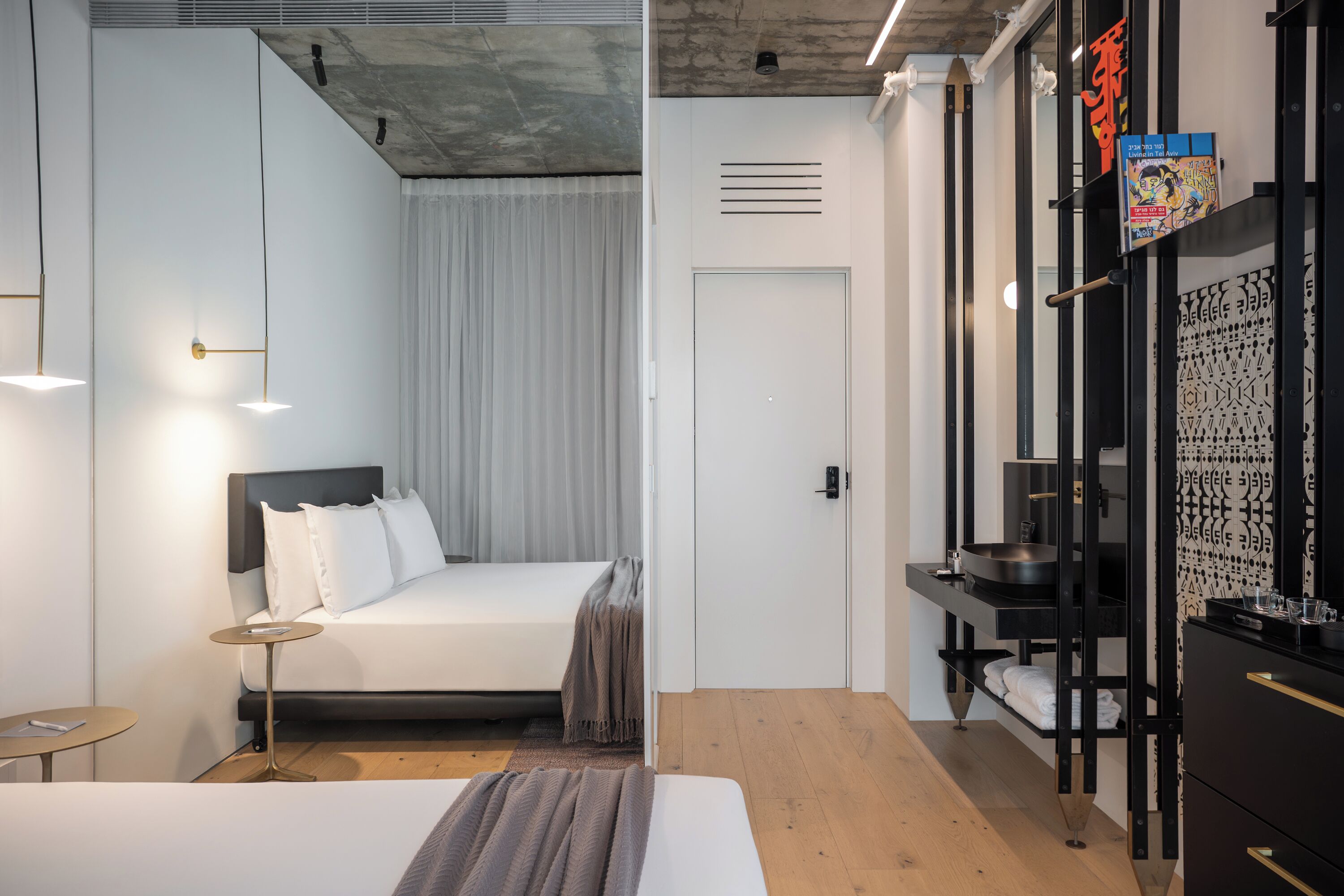 A modern hotel room with a bed, bedside table, and a wardrobe with a mirror.