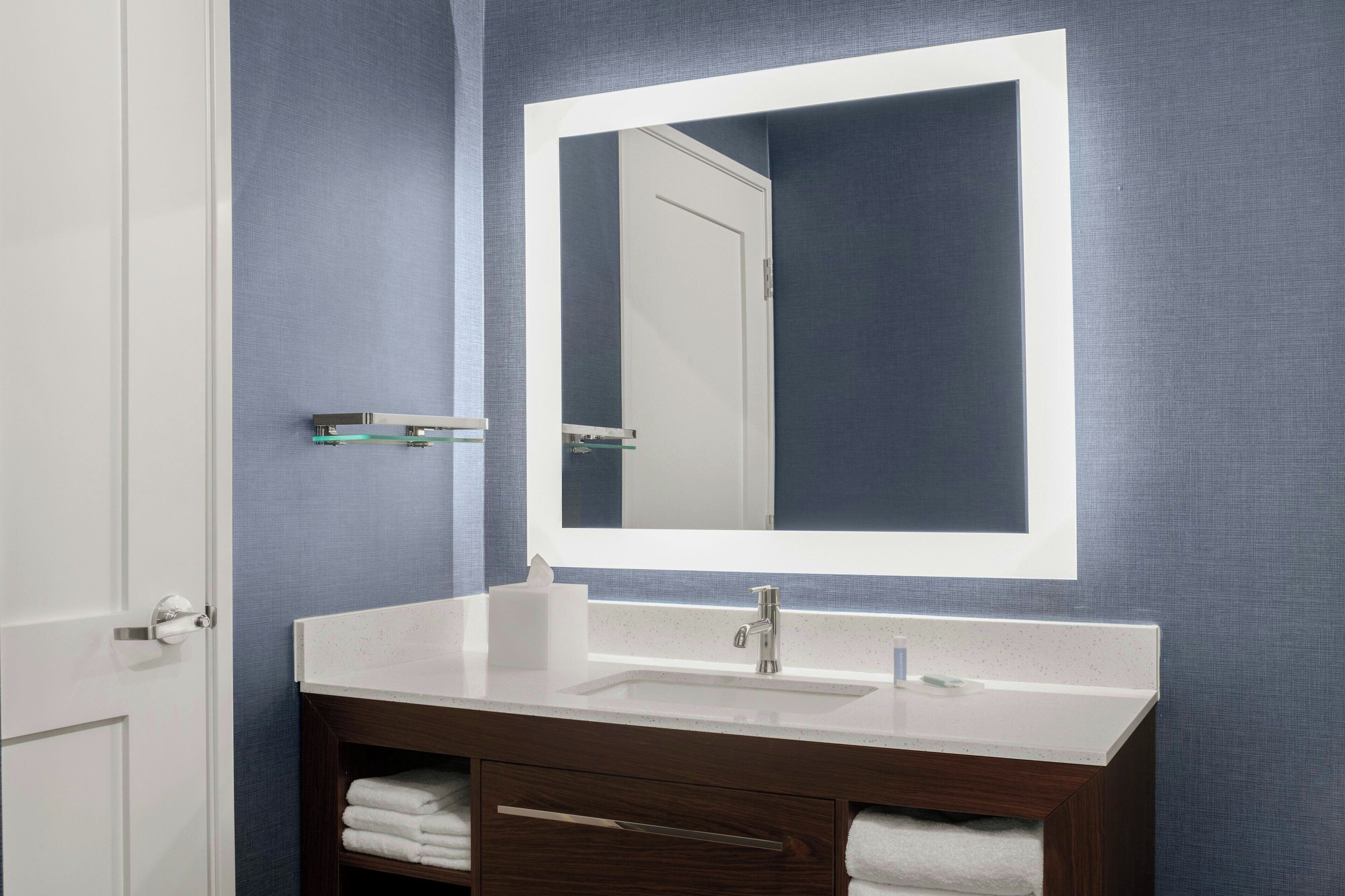 A bathroom with a white sink, a mirror, and a towel rack.