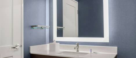 A bathroom with a white sink, a mirror, and a towel rack.