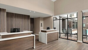 A reception area with two reception desks, a modern design with wooden paneling and marble accents, and a view of an outdoor patio through large glass doors. - Residence Inn By Marriott Yuma (Yuma)