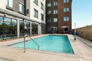 Una piscina al aire libre, sombrillas, sillones reclinables de piscina