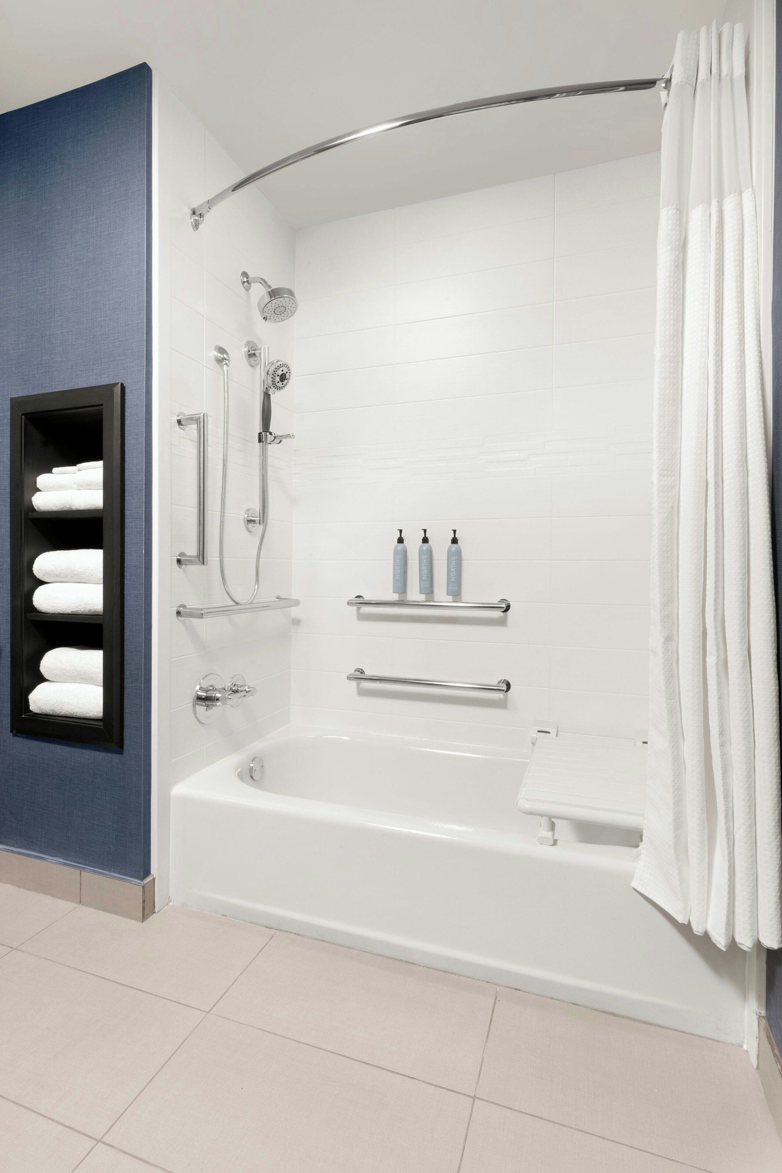 A modern bathroom with a bathtub, shower, and a towel rack with towels.