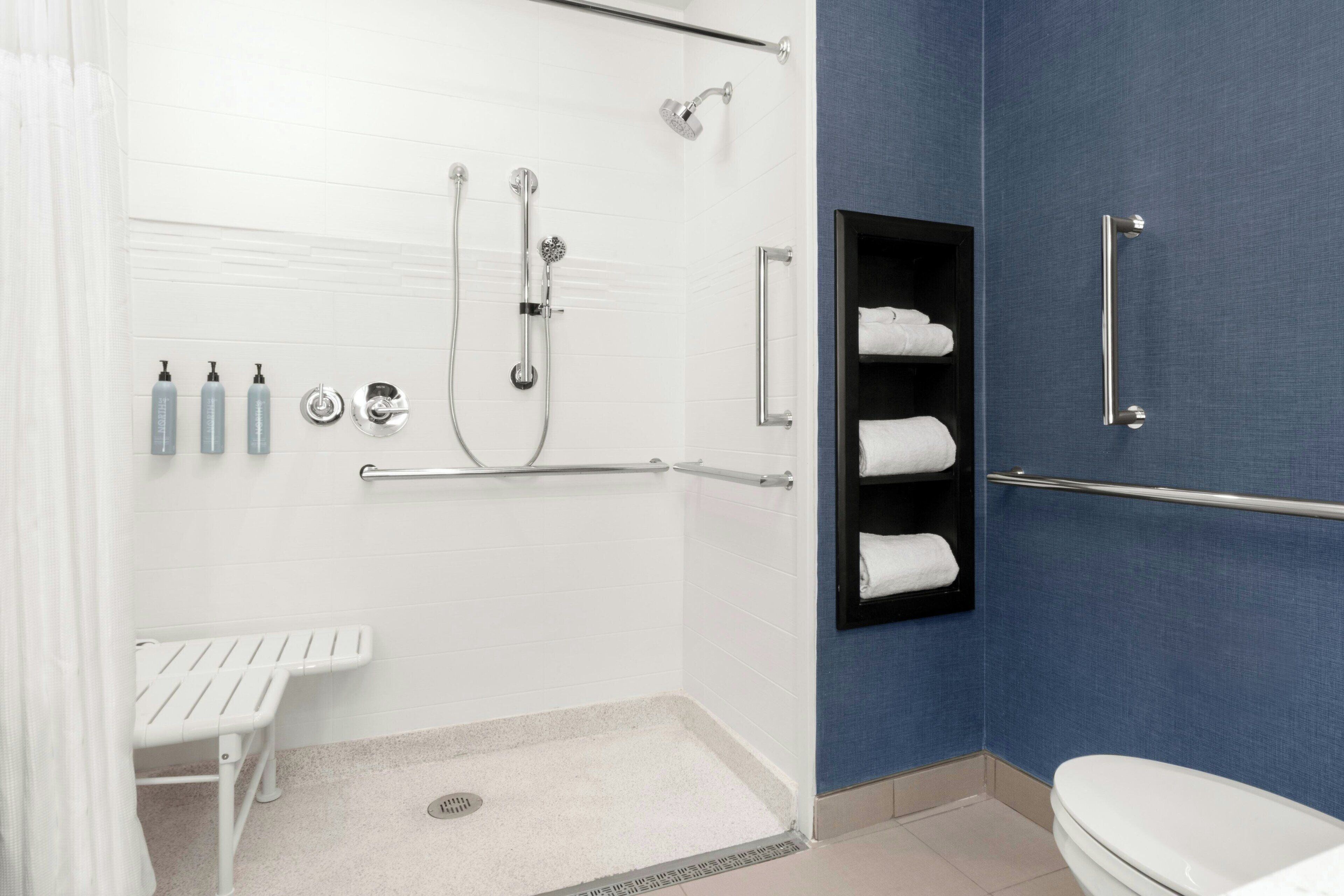 A bathroom with a shower, toilet, and a bench.