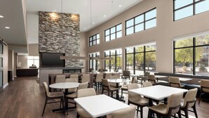 A spacious dining area with multiple tables and chairs, large windows, and a stone accent wall. - Residence Inn By Marriott Yuma (Yuma)