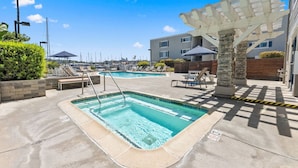 Ein Poolbereich mit zwei Pools, Liegestühlen und einer Pergola.