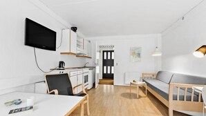 A modern, minimalist living space with a kitchen, dining area, and a sofa. - 1 bedroom cozy apartment in Nexø (Nexø)