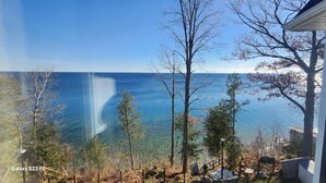 Blick vom Balkon auf ein Gewässer mit Bäumen und einem Gebäude.