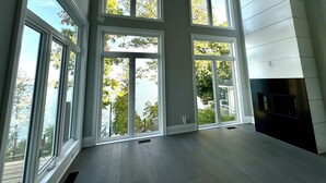 Ein geräumiger Raum mit großen Fenstern, einem Kamin und Blick auf einen See.