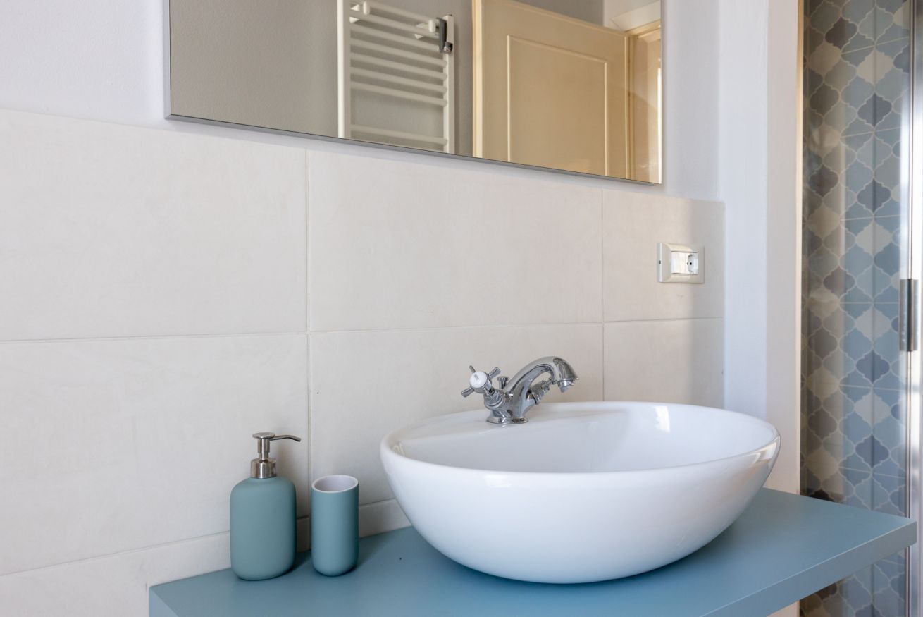 Une salle de bain avec un lavabo blanc, un miroir au-dessus et un porte-serviettes à gauche.