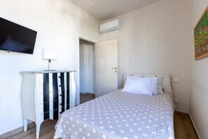 Une chambre à coucher comprenant un lit, une commode, un téléviseur et un appareil de climatisation.
