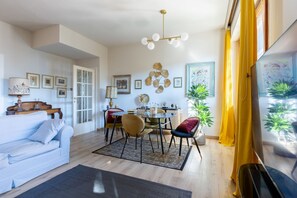 Un salon moderne comprenant un canapé, une table à manger, des chaises et un lustre.