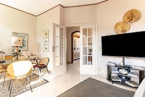 A living room with a dining area, a TV, and a bookshelf.