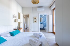 A hotel room with a large bed, a bedside table, a lamp, and a view of the bathroom.