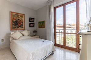 A bedroom with a bed, a nightstand, a lamp, and a view through a sliding glass door.