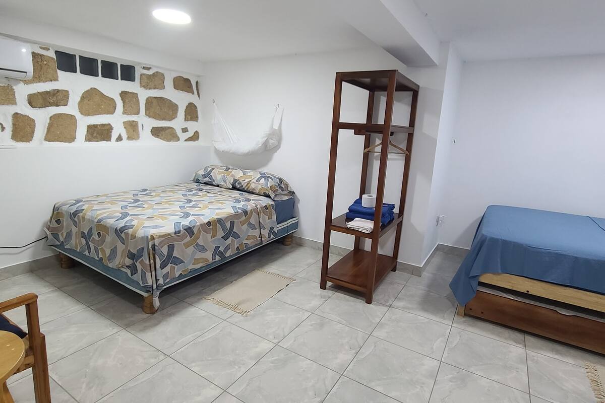 A bedroom with a bed, a wooden shelf, a blue-covered sofa, and a stone-patterned wall.
