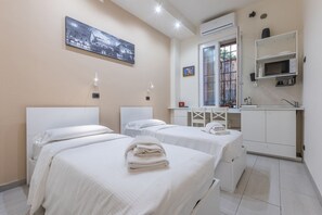 Habitación de hotel con dos camas, una kitchenette pequeña, un ventanal con vistas y un cuadro en la pared.