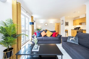 A modern living room with a grey sofa, a black coffee table, and a potted plant.