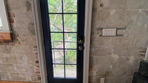 A room with a dark blue door, a brick wall, and a wooden floor. - Eola’s Gem in Downtown Orlando (Orlando)
