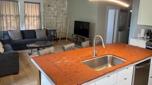A modern kitchen with a brick backsplash, a stainless steel sink, and a dining area with a table and chairs. - Eola’s Gem in Downtown Orlando (Orlando)