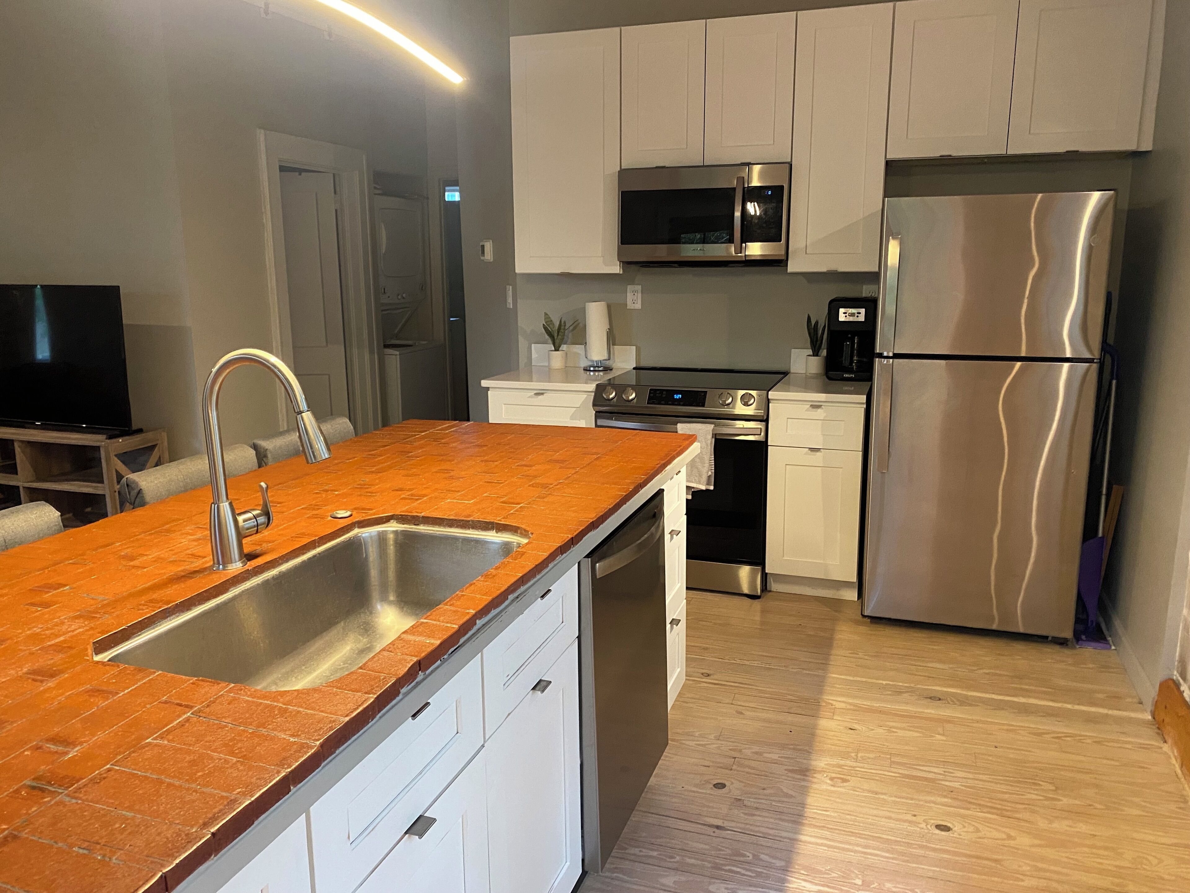 Una cocina moderna con armarios blancos, electrodomésticos de acero inoxidable y encimera marrón.