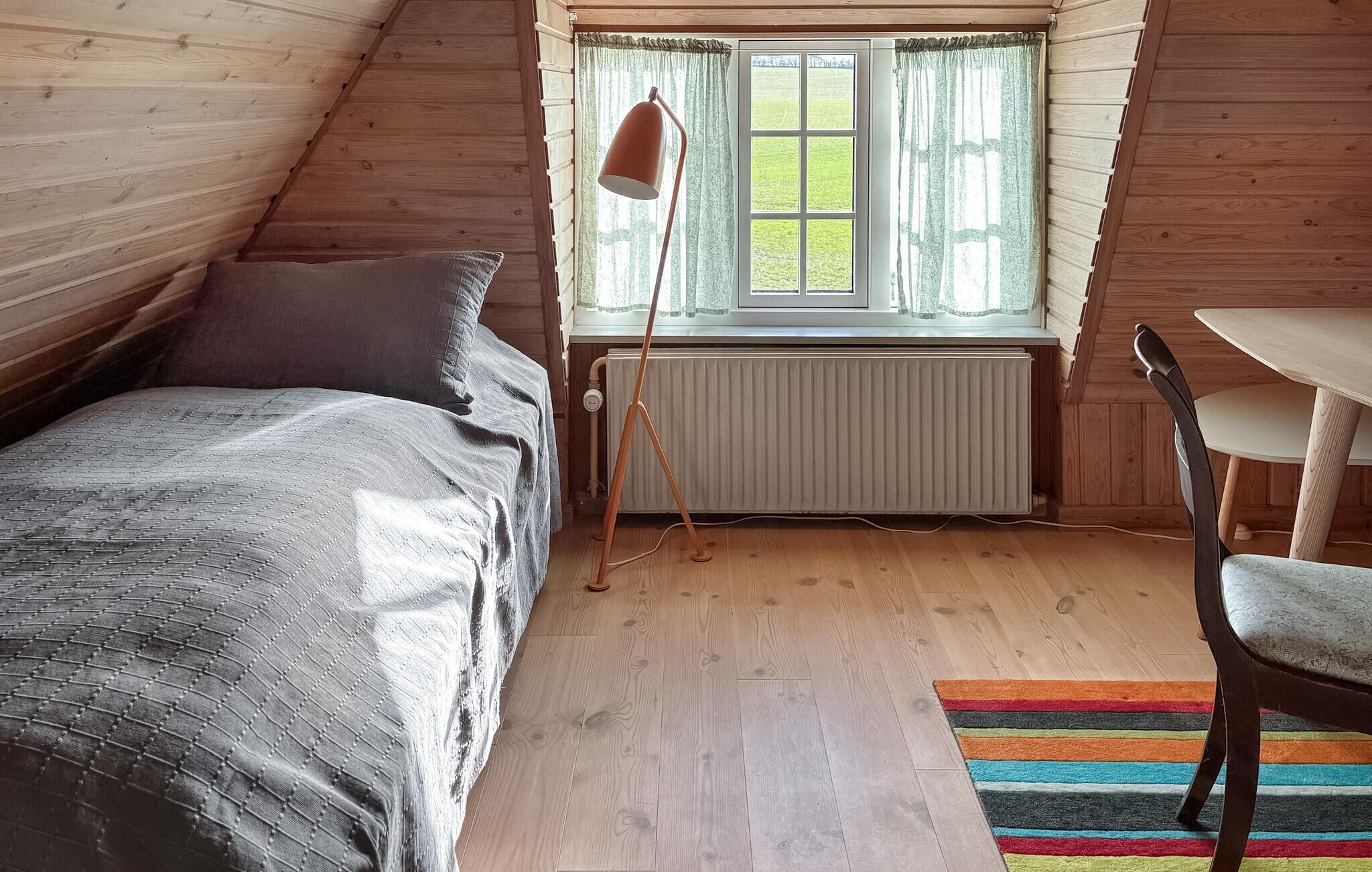Une chambre mansardée chaleureuse, avec un lit, une table et une chaise.
