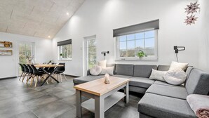 Una sala moderna con un sofá gris, una mesa de centro de madera y un comedor con mesa y sillas.