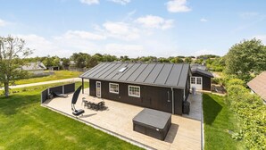 Una casa moderna con un patio amplio, una zona de estar exterior cubierta y una gran terraza.