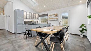 Una cocina moderna con armarios grises, una mesa de comedor de madera con sillas negras, y un ventanal que proporciona luz natural.