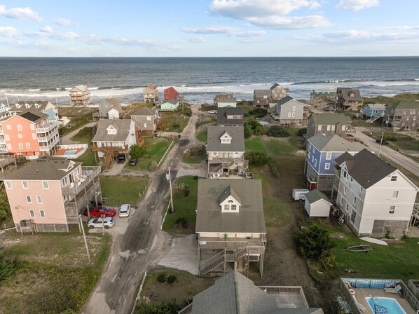 A coastal residential area with houses, a road, and a view of the ocean.
