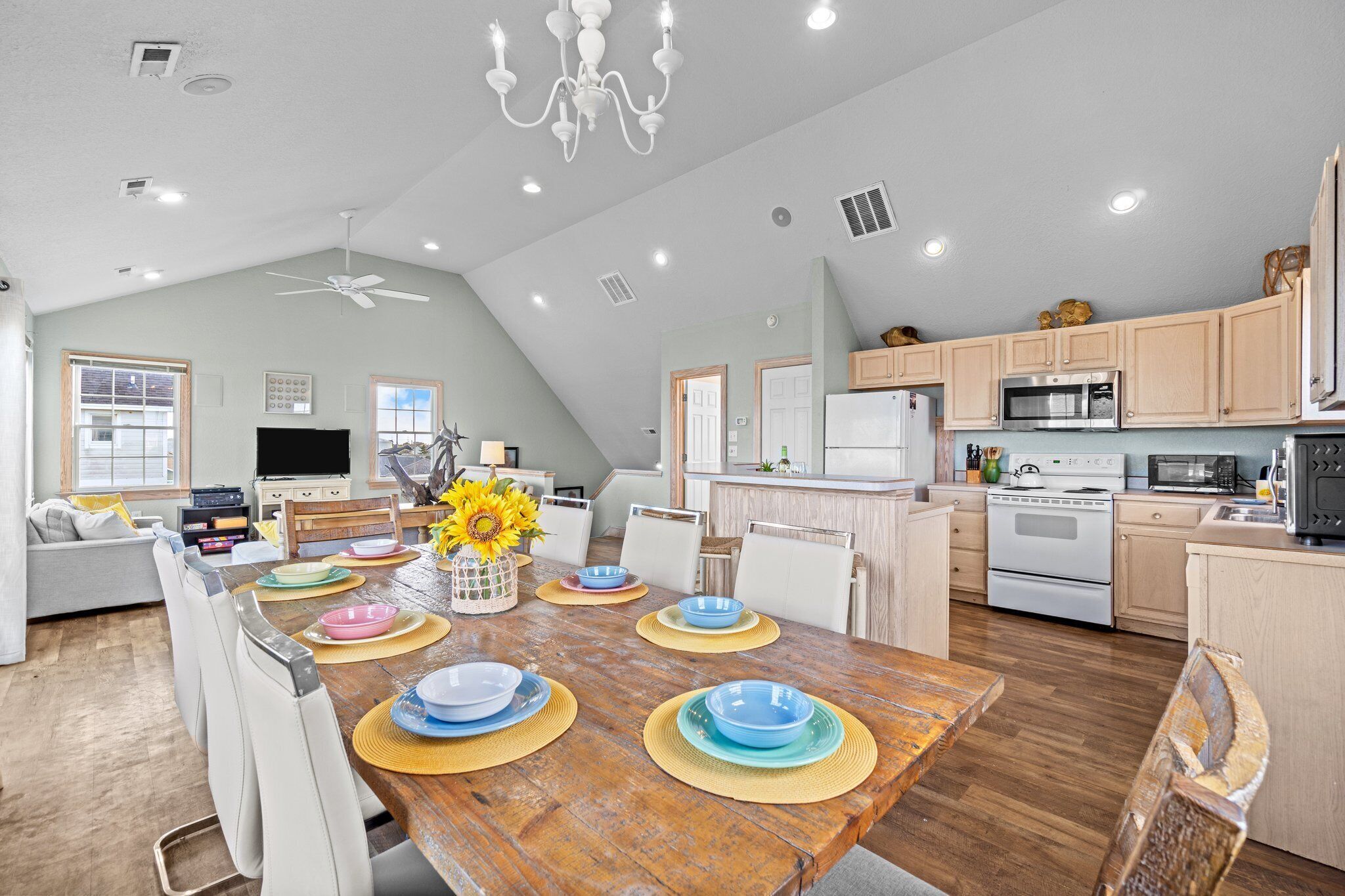 A spacious kitchen with wooden cabinets, a dining area with a wooden table set for four, and a ceiling fan.