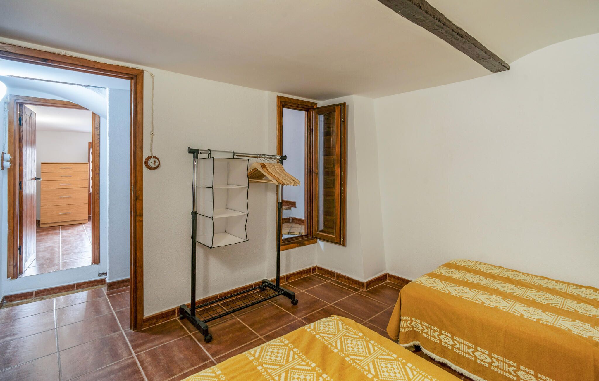 Une chambre à coucher comprenant un lit, une armoire, un portant à vêtements et une fenêtre.