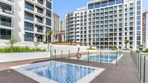 Ein modernes Gebäude mit einem Dachpool, umgeben von Grünflächen und anderen Hochhäusern.