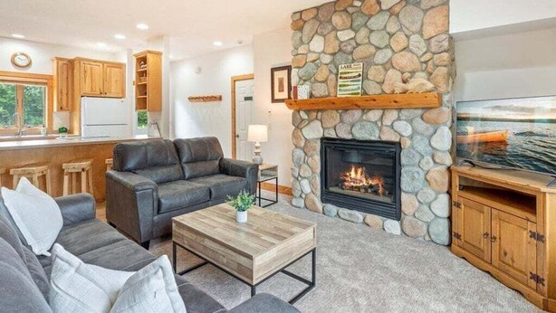 Ein Wohnzimmer mit Kamin aus Stein, einer Couch, einem Couchtisch und einem Fernseher.