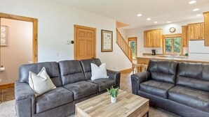 Ein Wohnzimmer mit zwei dunklen Sofas, einem Holztisch und einer Treppe, die in einen Küchenbereich führt.
