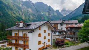 A traditional chalet with a balcony, surrounded by lush greenery and mountains. - Casa Alessandra 1 (Falcade)