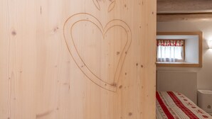 A wooden wall with a heart design and a window with curtains. - Casa Alessandra 1 (Falcade)