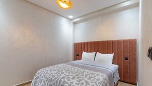 A bedroom with a bed, a headboard, and a ceiling light fixture. - Cosy new apartment Gueliz (Marrakech)