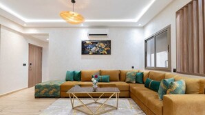 A modern living room with a sectional sofa, a coffee table, and a large window. - Cosy new apartment Gueliz (Marrakech)