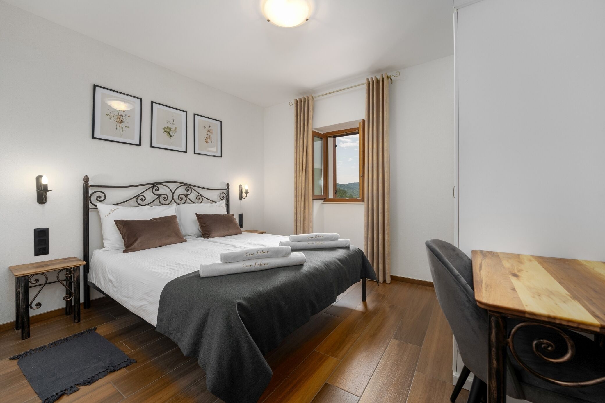 A bedroom with a bed, bedside tables, a desk, and a window with curtains.