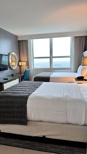 A hotel room with two beds, a desk with a chair, a TV, and a large window with curtains. - Breathtaking Direct Bay Views: 2/2.5 Condo includes Parking (Miami)