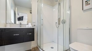 A modern bathroom with a glass-enclosed shower, a white toilet, and a dark wooden vanity. - Frankton Breeze 1 | Close to Queenstown CBD (Queenstown)