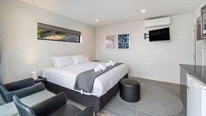 A modern hotel room with a large bed, a desk, and a TV. - Frankton Breeze 1 | Close to Queenstown CBD (Queenstown)