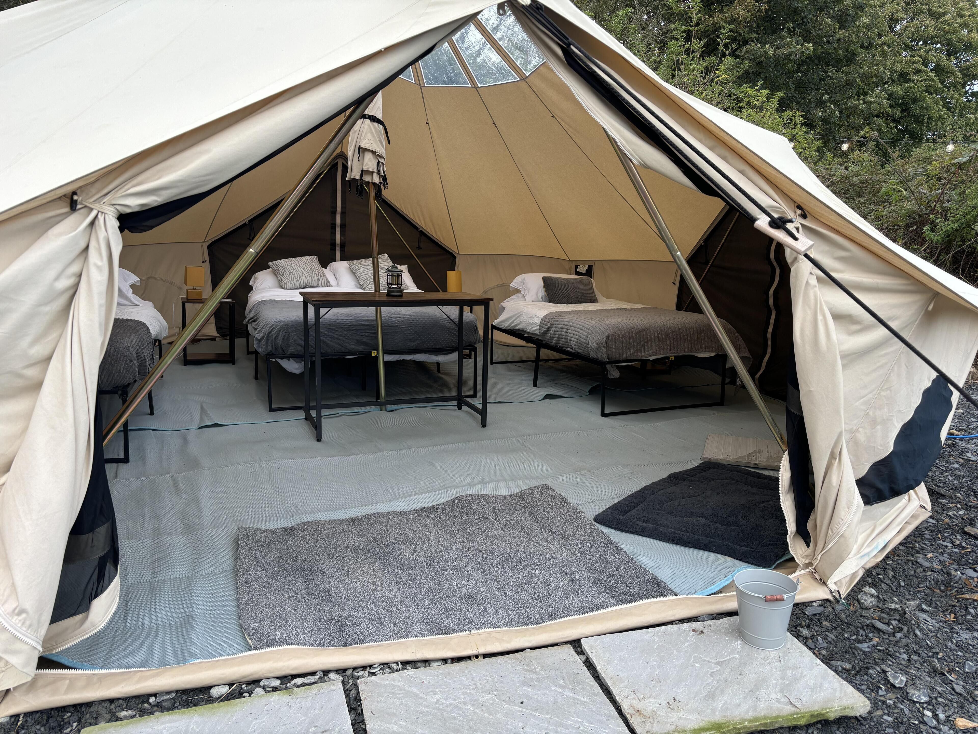 A tent with two beds, a table, and a lantern.