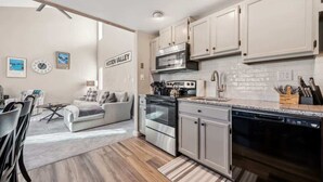 Eine moderne Küche mit Edelstahlgeräten, weißen Schränken und einem Essbereich mit einer Couch und Stühlen.
