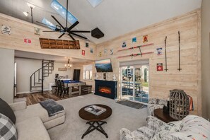 Un salon spacieux équipé d’une table de billard, d’une cheminée et d’un ventilateur de plafond.