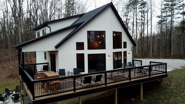 A modern house with a deck, large windows, and a garage.