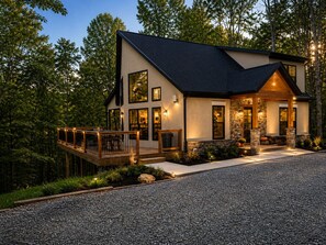 A modern two-story house with a deck, stone accents, and a gravel driveway. - The Quana -  Hot tub|Huge Entertainment Room (Logan)