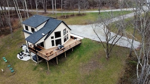 A two-story house with a deck, outdoor seating, and a fire pit.