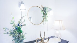 A wall-mounted mirror with a gold frame, two clear glass vases with green foliage, a wall sconce, and a table lamp. - Spacious 3 BR 2B House Sunnyvale Park (Sunnyvale)